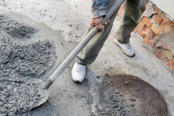 Handyman Spreading Cement With A Shovel